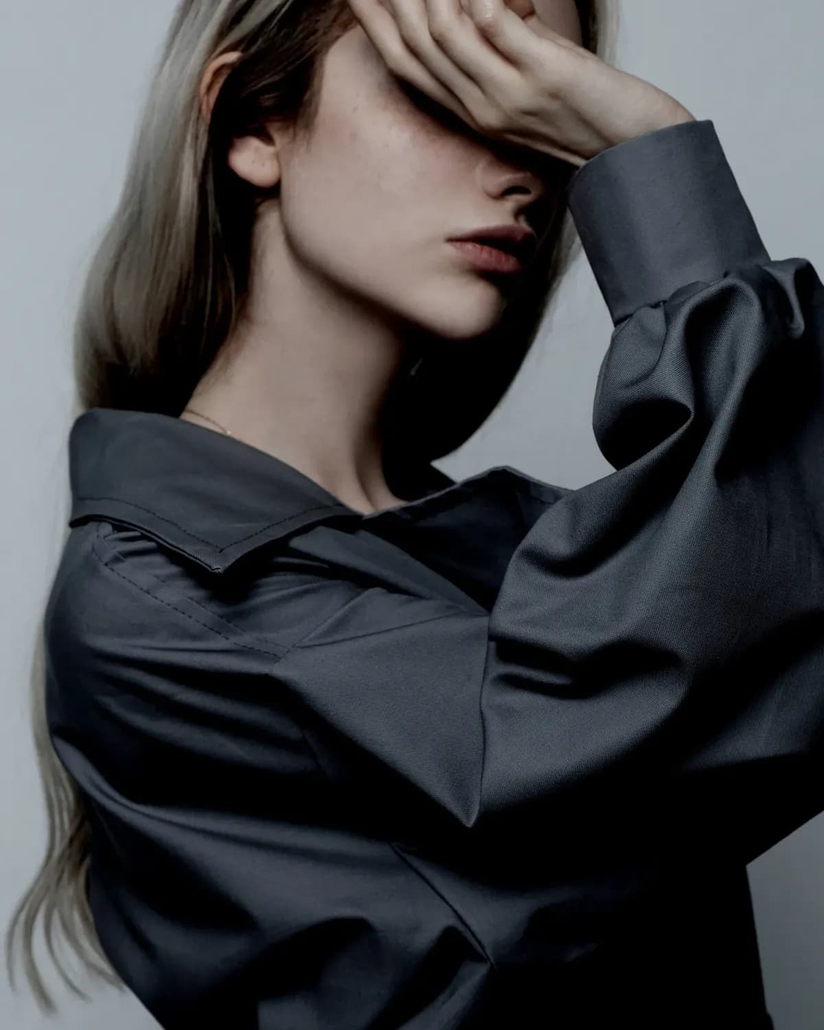 A model resting a hand over her eyes, in black and white
